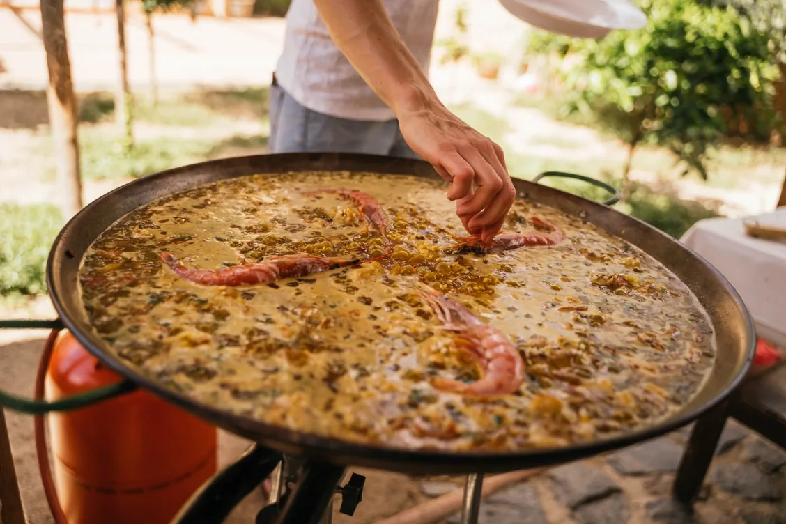 Arroz con gambas rojas cocinándose en paella al aire libre